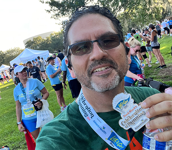 Man taking a selfie with Celebration of Running medal